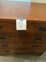 Close-up of chest drawer fronts showing wood grain details and metal handles.