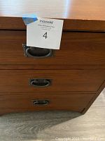 Close-up of the drawer handles and dovetail joinery indicating solid wood construction and overall good condition with some wear on the edges.