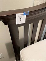 Close-up of the dark wood headboard featuring slatted design and smooth finish