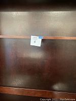 Back view showing dark wood grain panel with auction label