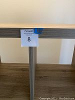 Close-up of shelf edge with auction tag number 8 attached.