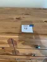 Close-up of pine wood grain and metal drawer knobs on chest of drawers.