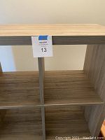 Close-up photo showing the internal compartments of the shelf with 8 cubby holes, showing woodgrain finish and laminated MDF material.