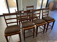 Front and side view photo of six solid rubberwood high-top chairs with brown seat cushions, arranged in two rows.