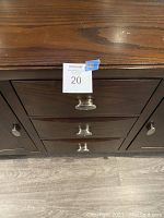 Close-up of the three drawers with metal handles and cabinet surface showing slight wear and scratching.