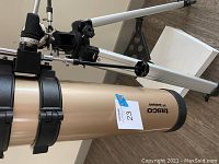 Close-up side view of the Tasco Luminova telescope showing the brand and part of the optical tube with a label number 23