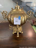 Front view of the solid brass antique Russian samovar on a wooden table.