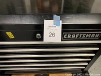 Front and top view of black Craftsman chest showing lock cylinder, drawer pulls and brand logo