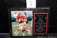 Photo plaque showing Joe Montana in red Kansas City Chiefs football uniform, holding the ball with gold autograph across the image, with achievement text on plaque beside photo.