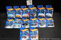 Photo showing all 14 Hot Wheels cars in original packaging arranged on a flat surface.