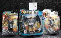 Photo showing three ThunderCats action figures M.O.C.: Claudus on the left, Mumm-Ra in the center, Lion-O on the right, all with unopened packaging from 2011.