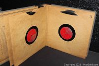 Photo of two open binder pages showing red label 78 RPM vinyl records in protective sleeves.