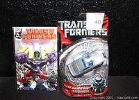 Transformers Recon Barricade Deception action figure in sealed packaging and Transformers comic book in protective bag shown together.