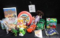 Photo showing entire lot with VHS tape, assorted sealed and loose toys including McDonald's toys and other kids meal collectibles.