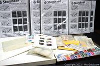 Overview photo showing 10+ Starsheet collecting sheets standing upright in the background, envelopes, packets, and stamp sheets arranged in the foreground.
