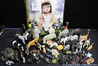 Full lot view showing the toddler costume in the background surrounded by various resin animal figurines of different species and sizes.