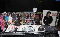 Photo showing a collection of vintage Musician and Electronic Musician magazines, Michael Jackson 'BAD' album cardboard posters, and a drum stand.