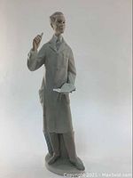 Full view of the Lladro figurine "The Teacher" showing the male figure in coat holding a book and pointer.