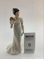 Front view of hand painted porcelain figurine of a woman in Regency style dress holding a fan.