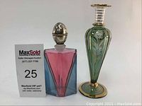 Front view of decorative bottle with stopper and tall colored glass vase side by side