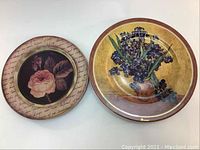 Two circular plates shown side by side: one is a Goebel Van Gogh collectible numbered plate depicting irises in a vase on a tan background, the other is a decorative plate with a pink rose center and cursive script border.