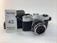 Front and side view of Tokyo Kogaku Topcon camera with lens and original case in background.