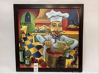 Framed print showing a colorful chef cooking in a kitchen scene, with checkered floor and various kitchen items.