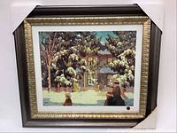 Framed numbered print titled 'Winter Afternoon' by Lauren Harris, showing snow-covered trees and house with two winter-clad figures in the foreground.
