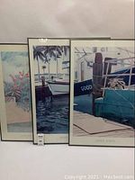 Photo showing three framed posters arranged close together including two nautical boat prints and one floral print