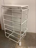 Full view of white metal storage basket rack with three sliding baskets and metal frame.