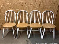 Four solid wood kitchen chairs, natural wood seats with white painted spindle backs and legs, lined up front-facing.