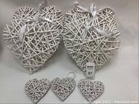 White wicker hearts displayed against a neutral background. Six large hanging hearts and three smaller hearts laid below.