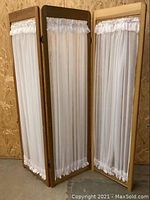 3-panel folding room divider shown fully open with wood frames and white sheer curtains in ruffled design at top and bottom