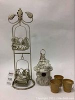 Full view of metal plant stand, ceramic birdhouse, and three small metal pots on a white backdrop.