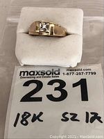 Front view of ring on white display cushion with lot tag showing “18K Sz 12”