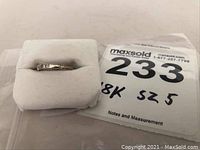 View of the gold ring displayed on a white cushion next to a label indicating 18k gold and size 5.