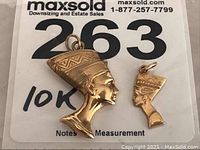 Photo showing both 10k gold Nefertiti charms side by side on labeled card.