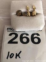 Photo of the pair of 10k gold pierced earrings in the shape of arrows on a grey display card with auction tag 266