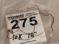Full view of the 10k gold chain laid out over the lot number card showing the length and chain style.