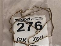Full view of 20-inch 10k gold necklace chain laid on card with MaxSold lot number