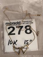 Full view of the 15 inch 10k gold necklace laid over a MaxSold tag showing lot number and size details.