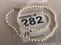 Full view of the 16-inch pearl necklace laid out with lot number label visible