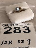 Ring on display cushion with lot number card showing #283 and '10K sz7'