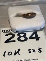 Full view of the ring showing the textured gold surface and size marking on display foam.
