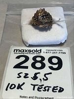 Front view of ring on white display pad with MaxSold tag reading '289 size 5.5 10K tested'