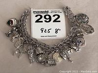 Full view of sterling silver charm bracelet and attached charms with measurement and lot card