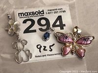 Three sterling silver pendants displayed on a surface with a MaxSold label showing lot number 294 and mark 925 indicating sterling silver content.