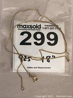 Full view of gold washed sterling silver neck chain with 18 inch measurement note and lot number card under it.