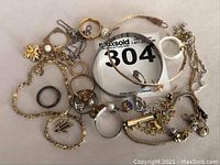 Overall assortment of jewelry pieces and loose parts on white background with lot number card