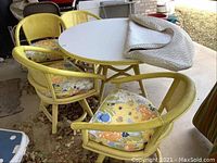 Full view of yellow round outdoor table with four matching swivel chairs and floral cushions.